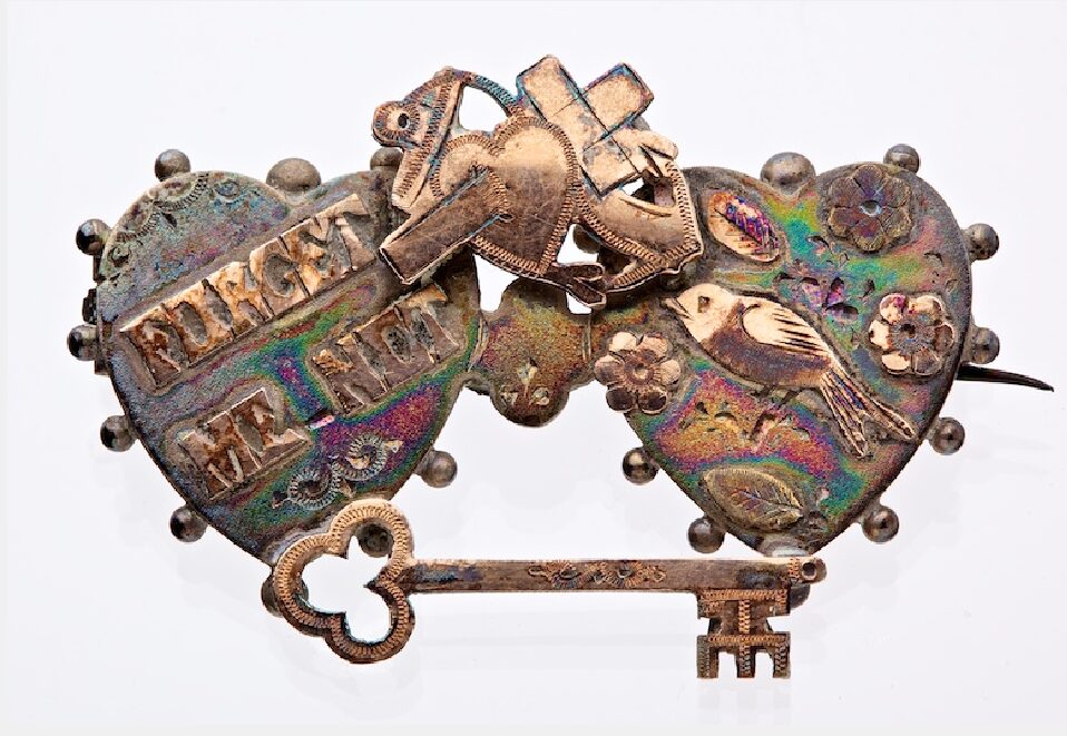 Silver brooch, two hearts above a key and on the left heart inscribed the words ‘Forget me not’.