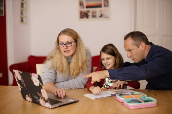 Image of a woman and a man sat round a computer pointing with a young child.