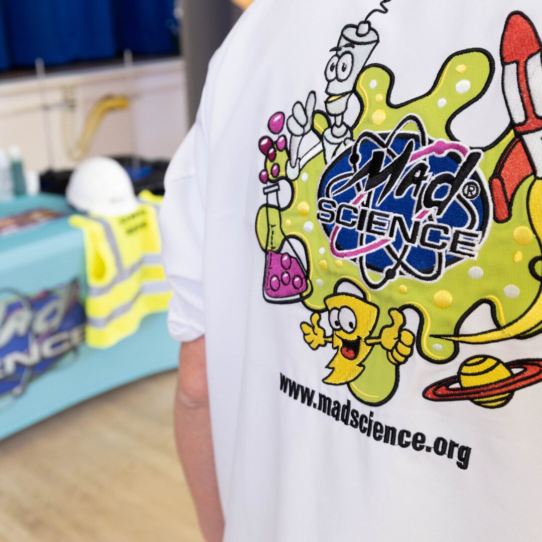 A child wearing a white t-shirt featuring the mad science logo.