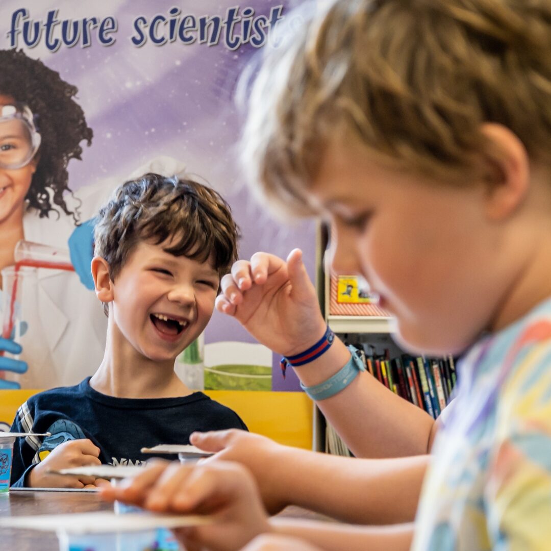 Two children smiling and laughing at a science show.