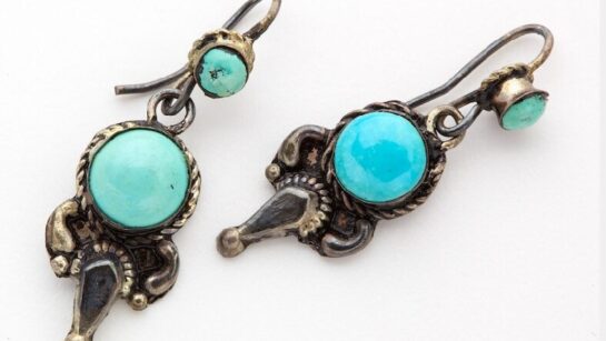 Earrings featuring a blue opaque gem surrounded by metal.