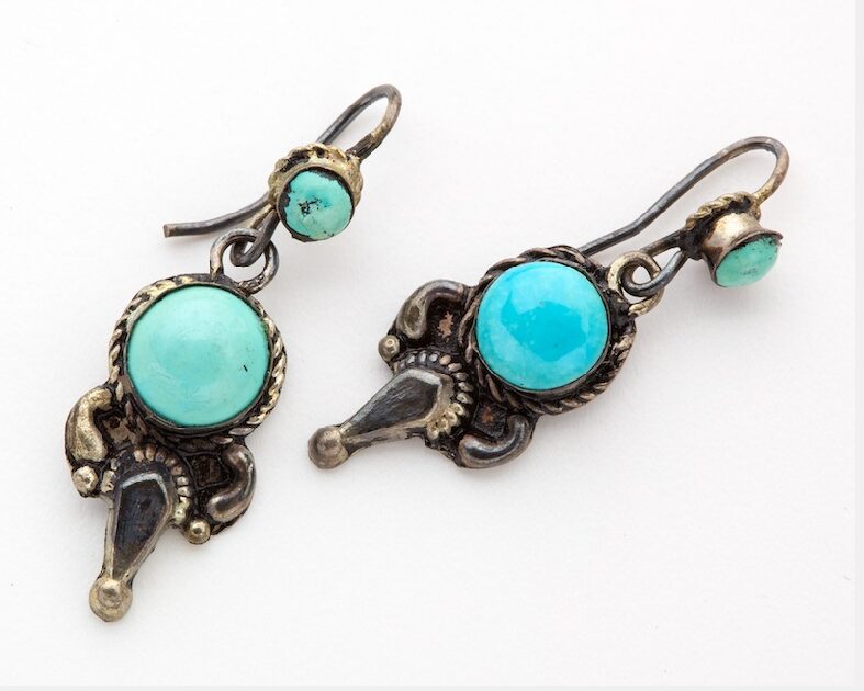 Earrings featuring a blue opaque gem surrounded by metal.
