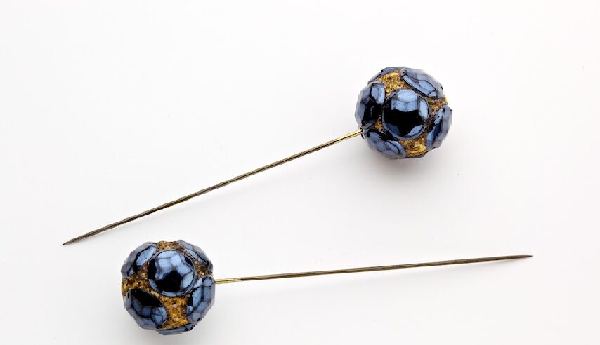 Two blue and gold hat pins.