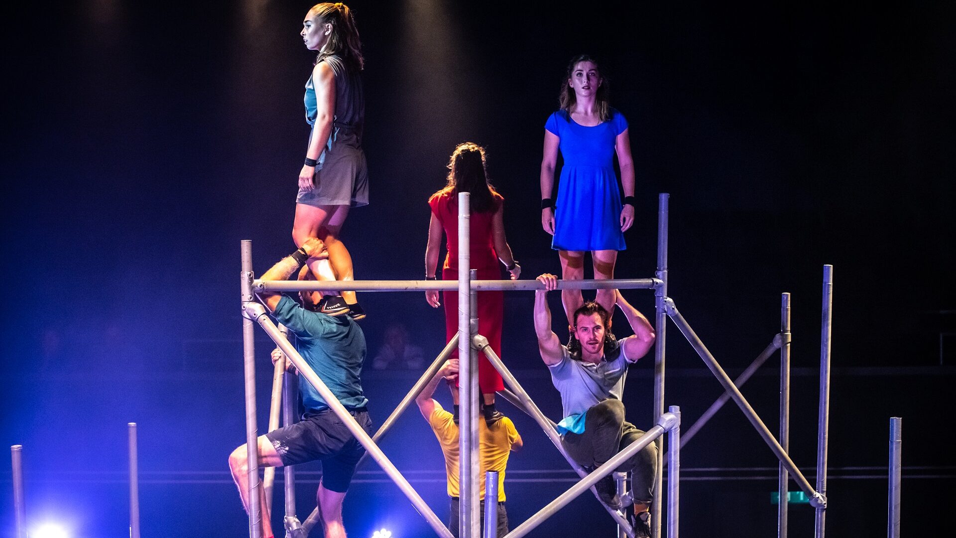 Image of performers standing on different level metal beams.