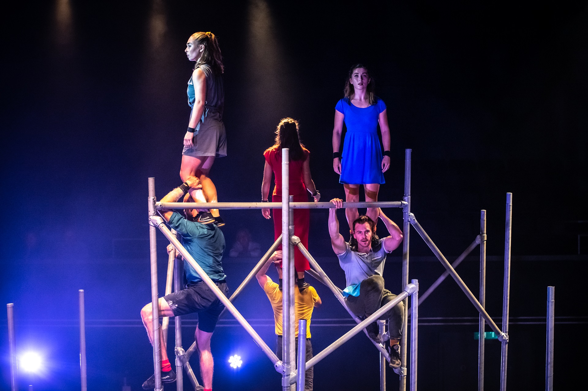 Image of performers standing on different level metal beams.