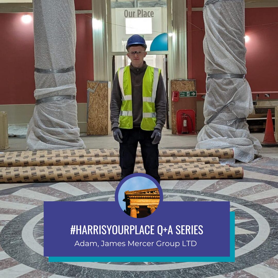 A person wearing a hard hat with a high vis jacket stands in the rotunda space of the Harris.