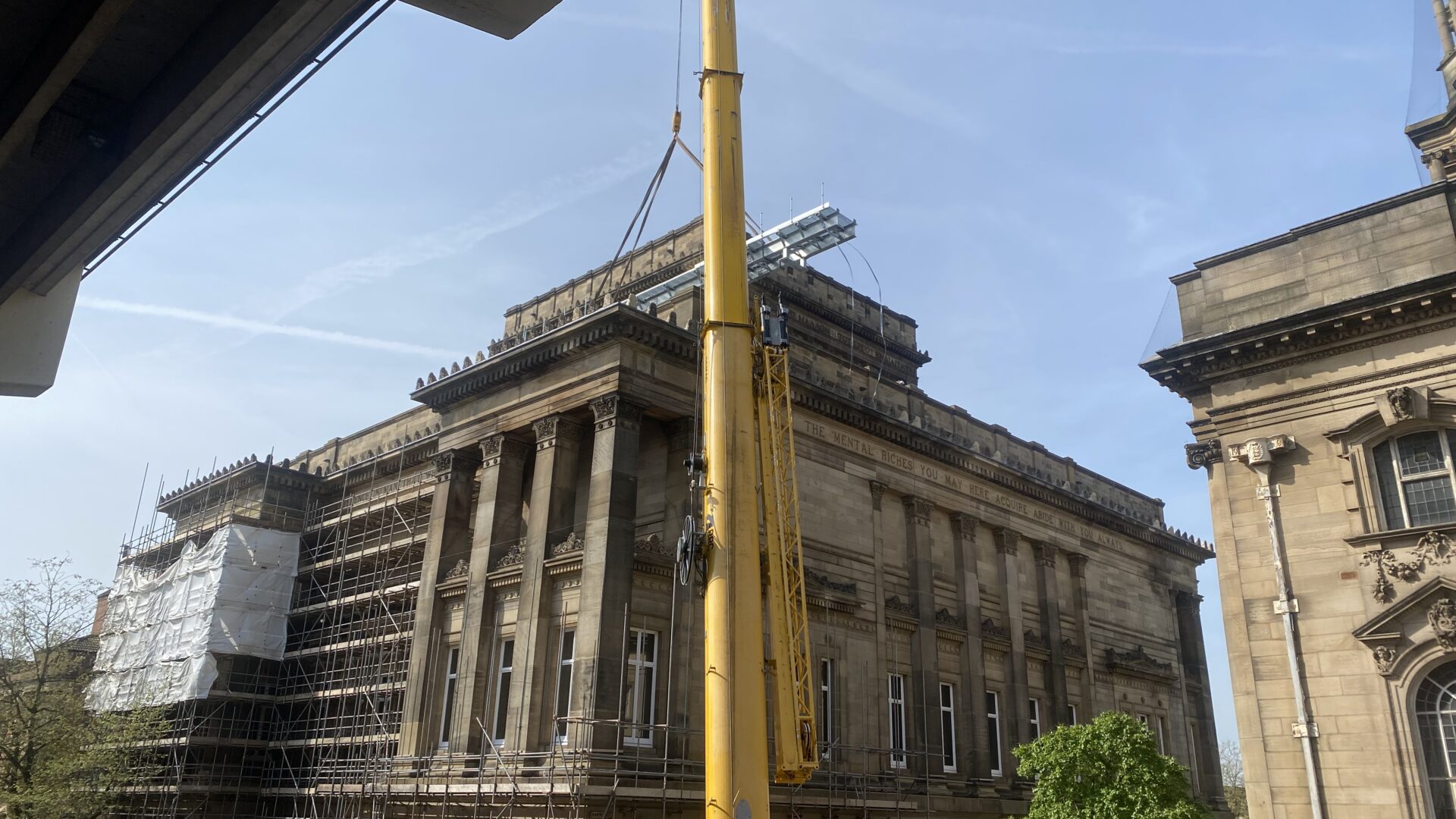 Image of a large yellow crane above The Harris building