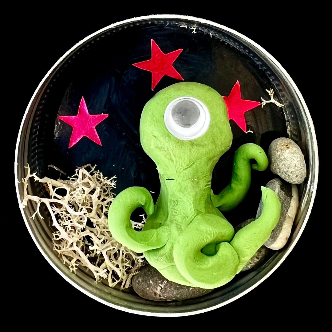 A small crafted alien in a tin.