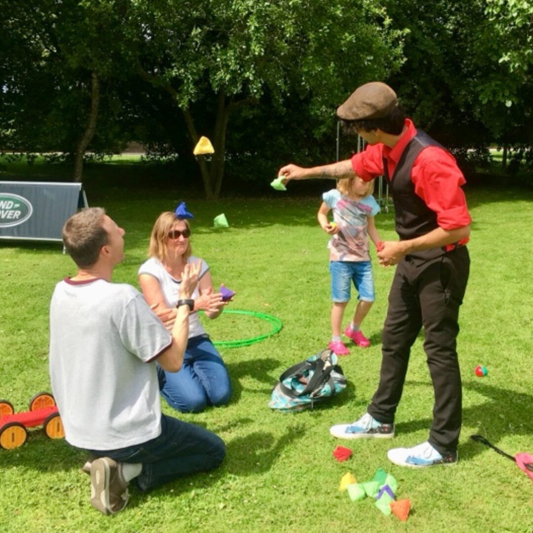 A group of people watching a person juggle bean bags.