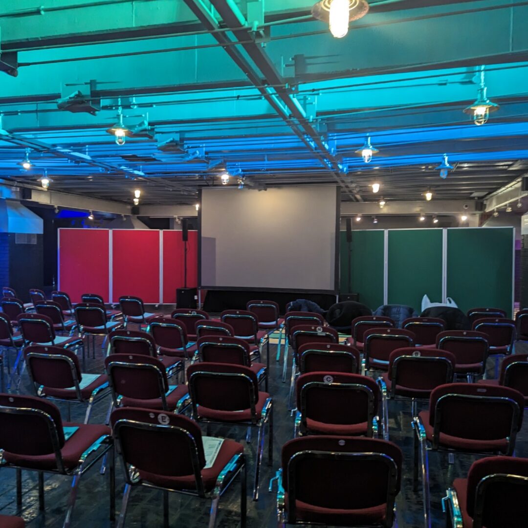 Rows of seating and a large screen in the guild hall foyer.