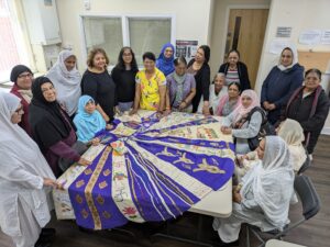 Image of people stood around a table draped in a blue and gold dress.