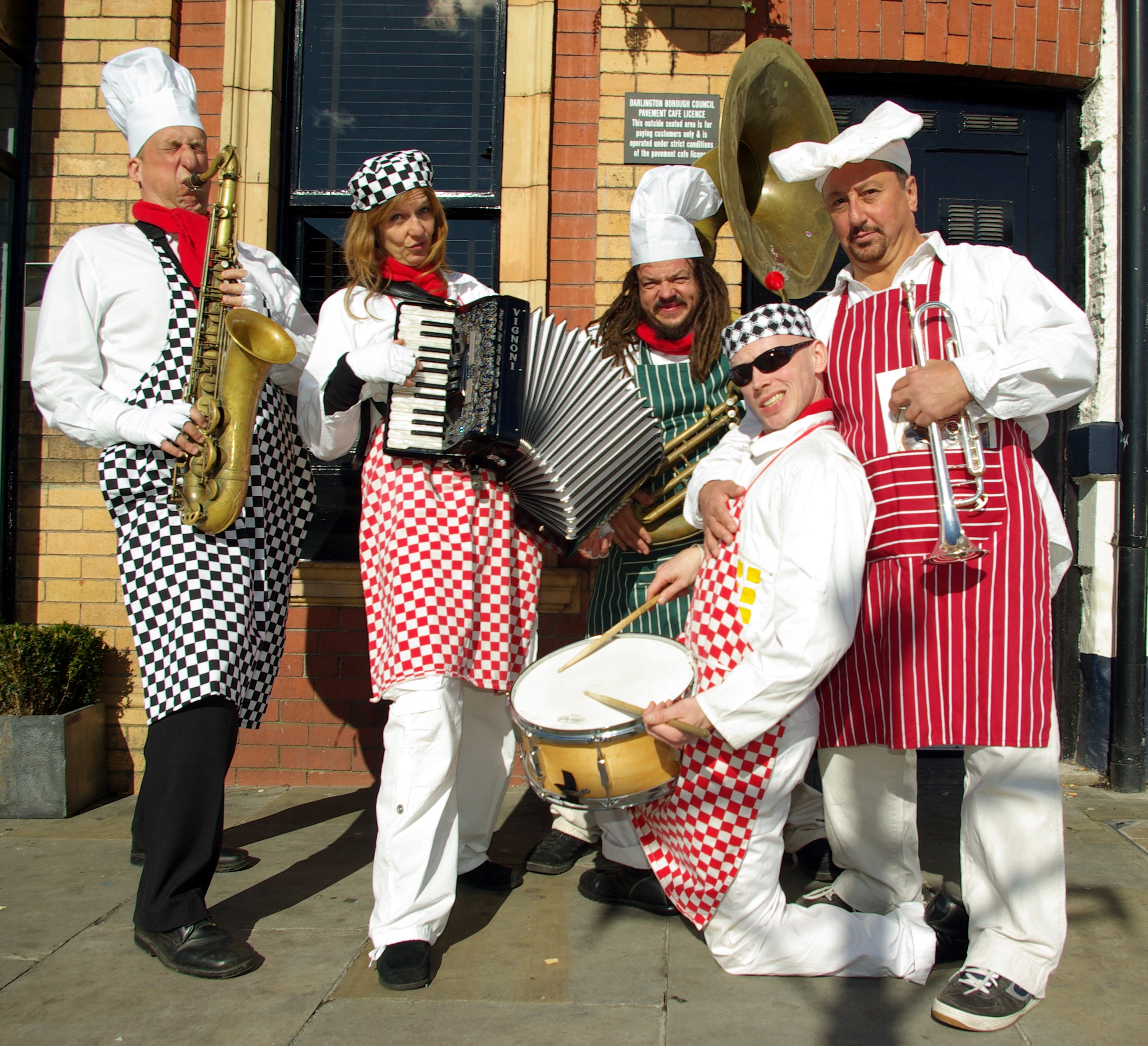 A group of people with instruments wearing chef hats and aprons.